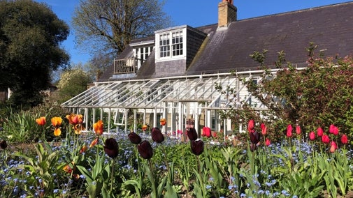 Monk's House, conservatory side and view of the front beds with red tulips and forget me nots